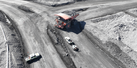 a mine road and intersection showing a red truck and white vehicles