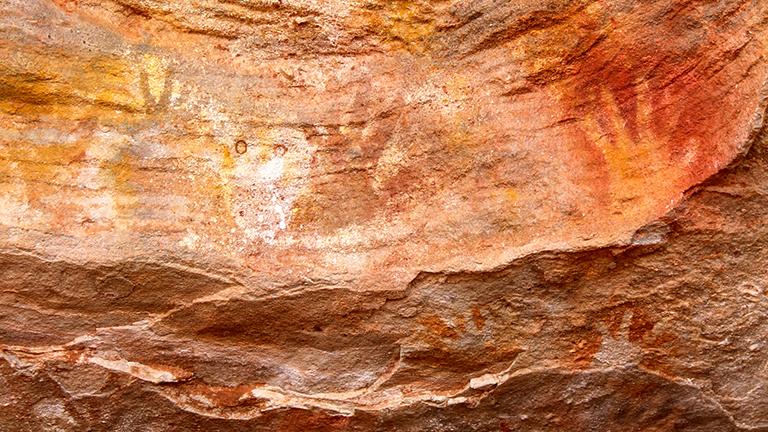 Aboriginal art at Mutawintji National Park. Artwork features handprints at various sizes on rock wall.